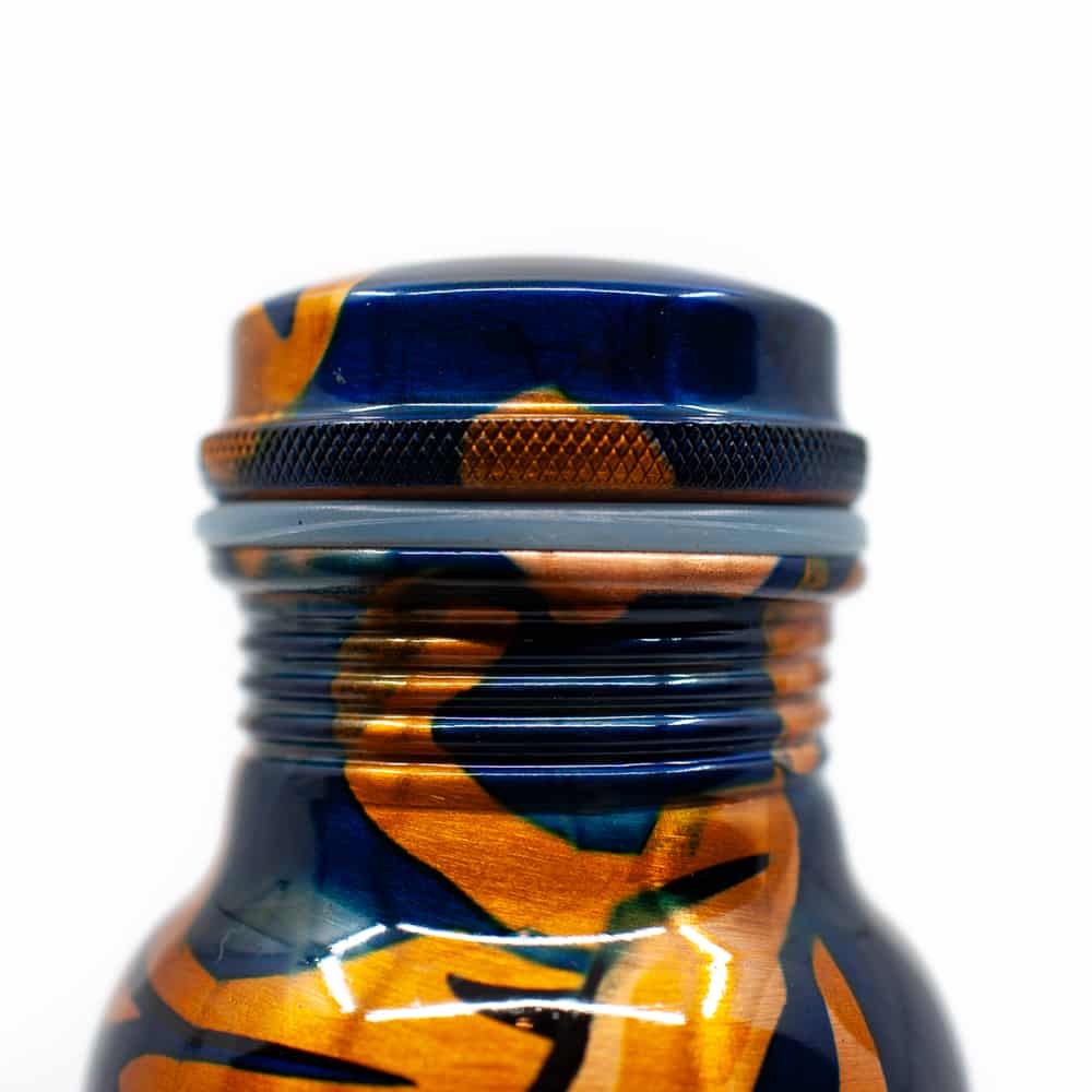 detalle de parte de arriba de una botella de agua de cobre azul con detalles dorados