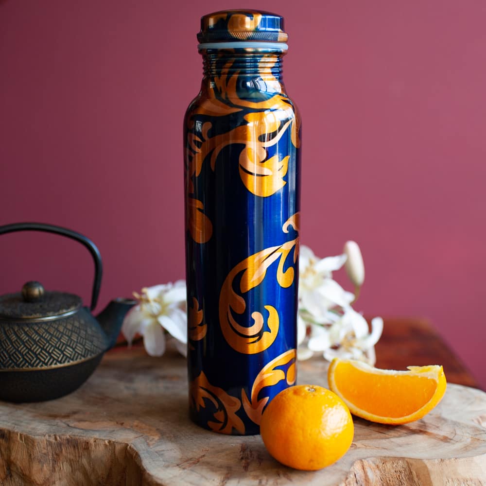 botella de agua de cobre azul con detalles dorados con rodajas de naranja